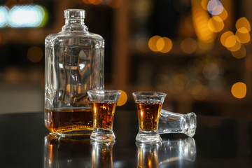 Bottle and glasses of whiskey on table in bar