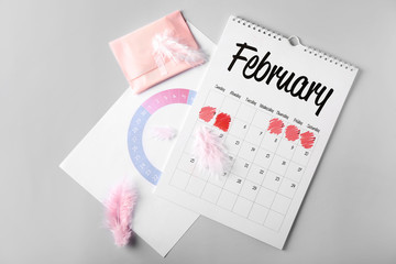 Calendar with menstrual pad on grey background
