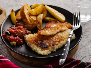 Fried fish with tomato-olive sauce and potatoes.