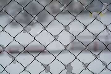 Wire fence in the snow. Fence background. Metallic net with snow. Metal net in winter covered with snow. Wire fence closeup. Steel wire mesh fence vintage effect.