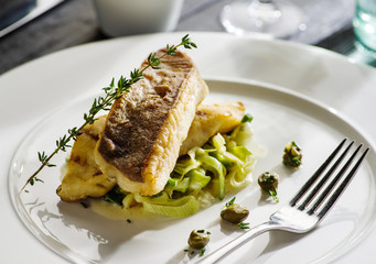 Fillet of halibut on a pillow of stewed leeks on the white plate. - obrazy, fototapety, plakaty