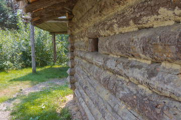 Seitlicher Blick auf eine Blockhütten Wand mit Fenster