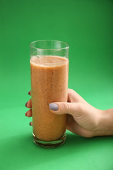 Female hand with glass of healthy smoothie on color background