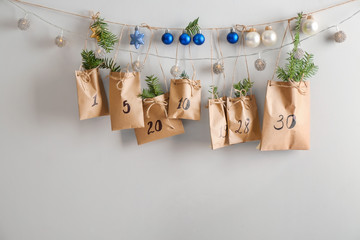 Paper bags with Christmas gifts and drawn numbers hanging on wall