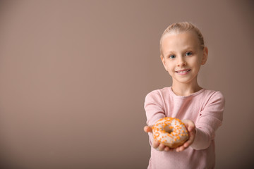 Cute little girl with donut on color background