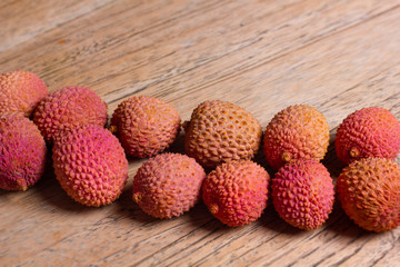 Raw pink and orange lychees on a wooden background