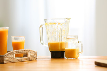 Blender and mason jar with tasty smoothie on wooden table