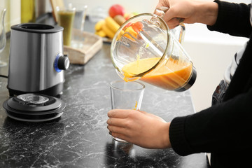 Woman preparing tasty smoothie in kitchen
