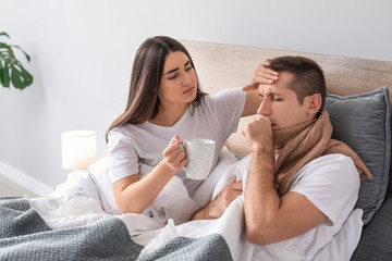 Woman taking care of her husband ill with flu at home