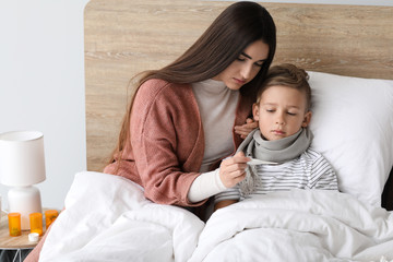 Mother taking care of his son ill with flu at home