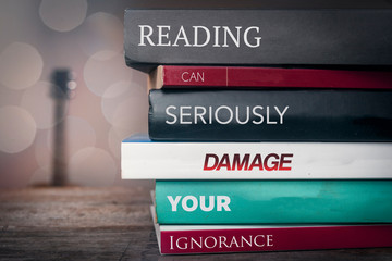 Pile of books with text saying "Reading can damage your ignorance"