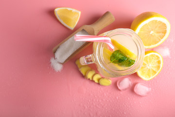 Mason jar of tasty cold lemonade on color background