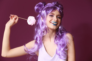 Fototapeta premium Beautiful young woman with unusual makeup and sweet lollipop on color background