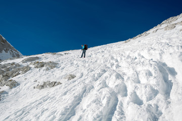 Naklejka na ściany i meble Female alpinist ascending a steep snowy slope.