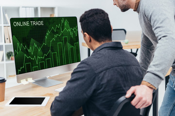 cropped shot of business colleagues using desktop computer with online trade graphs on screen in office