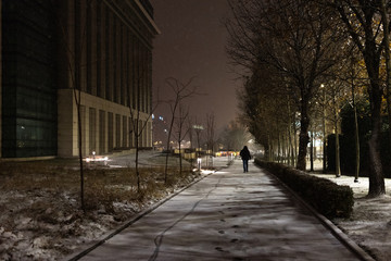 Frosty night - Snow sidewalk - Nightly snow falls over buildings and people from city on Christmas holyday time