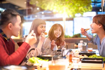 Zelfklevend Fotobehang gelukkige Aziatische jonge Groep die in het restaurant eet? © Tom Wang