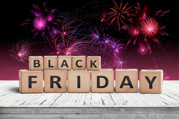 Black friday sign on a wooden table with fireworks