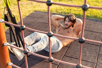 Handsome young man exercising crunches in the park
