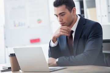 focused young businessman in suit working with laptop in office