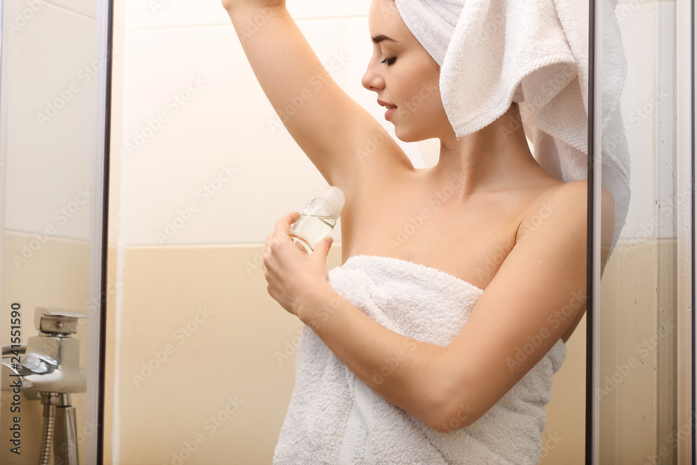 Wall mural Beautiful young woman with deodorant in bathroom