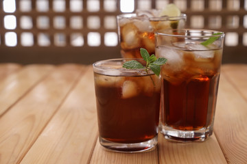 Glasses of tasty cold cola drink on wooden table