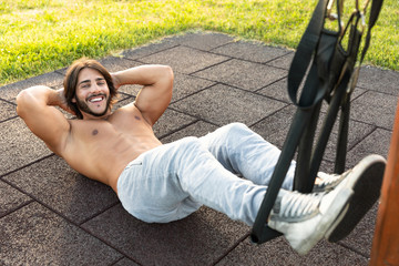 Handsome young man exercising crunches in the park