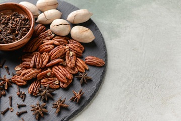 Slate plate with pecan nuts and spices on light background