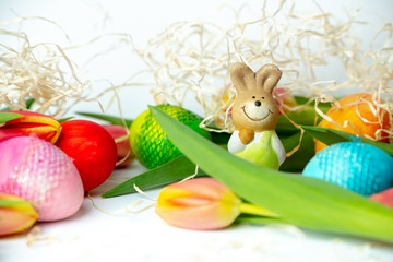 Fototapeta na wymiar Easter eggs in vibrant pastel colors and fresh tulips on a white background