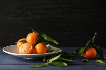 Plate with tasty tasty juicy tangerines on wooden table