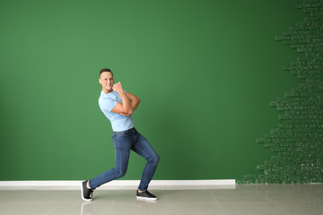 Young man dancing near color wall