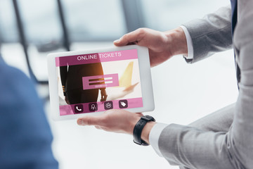 partial view of businessman holding digital tablet with online tickets app on screen