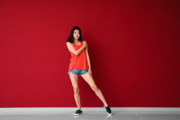 Fototapeta na wymiar Female Asian dancer near color wall