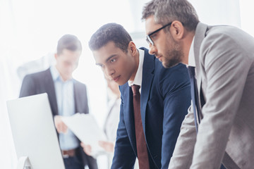 focused serious businessmen working with desktop computer in office