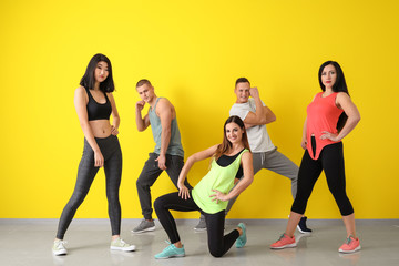 Fototapeta premium Team of young dancers near color wall
