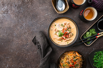 Spicy soup with coconut milk and chicken, Thai food called Tom Kha Gai on black table, top view