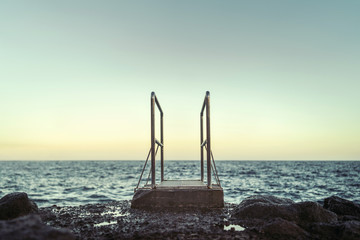 Fototapeta premium Pier out to the ocean on the beach with stones.