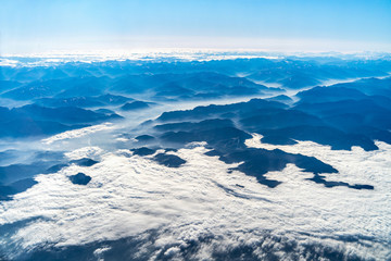 Landscape view of Alpine mountains with clouds from the plane