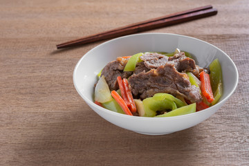 stir fried beef with banana pepper in a ceramic bowl on wooden table. hot and spicy homemade style food concept.