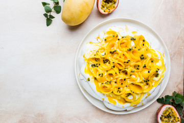 Meringue cake Pavlova with fresh mango and passion fruit and whipped cream on slate, stone or concrete background, top view