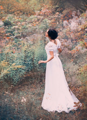 delightful princess in a long white dress got lost in a distant forest, listens to the noise and singing of birds, stands still waiting, a fairytale fairy in a long silk vintage elegant white dress