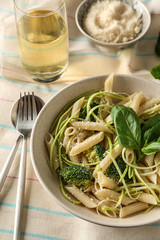 Plate with tasty pasta and green vegetables on table