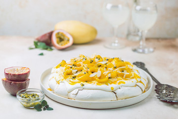 Meringue cake Pavlova with fresh mango and passion fruit and whipped cream on slate, stone or concrete background