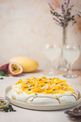 Meringue cake Pavlova with fresh mango and passion fruit and whipped cream on slate, stone or concrete background