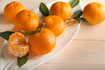 Plate with tasty tangerines on wooden table