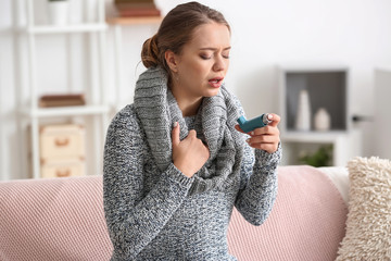 Young woman with inhaler having asthma attack at home