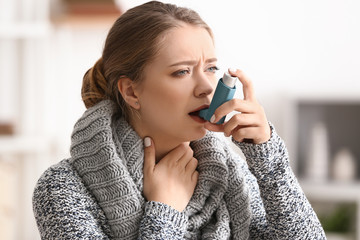 Young woman with inhaler having asthma attack at home