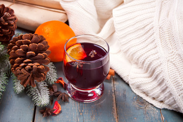 Wineglass with Christmas mulled red wine with spices and fruits on a wooden rustic table.