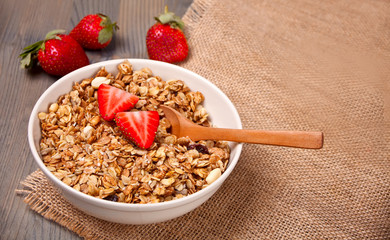A plate with muesli and strawberries on the wooden table