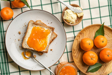 Bread with butter and tasty tangerine jam on table